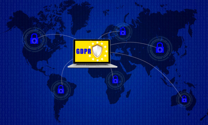 Kłódka na laptopie komutera nad mapą świata i symbolizująca ogólne rozporządzenie o ochronie danych UE lub RODO.