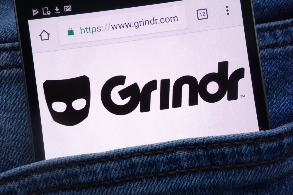 Logo aplikacji GRINDR na ekranie telefonu w tylnej kieszeni spodni