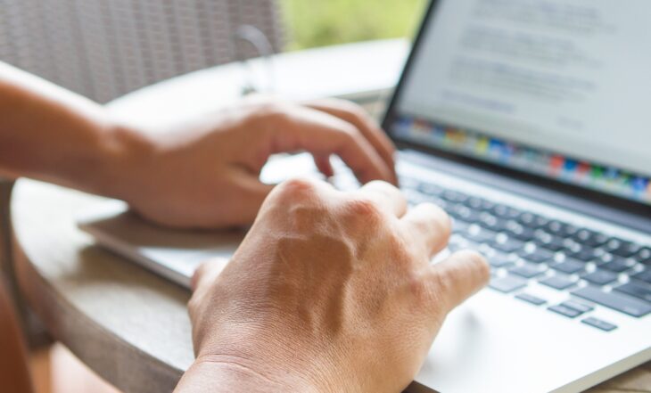 Ręce pracownika piszące na klawaiturze laptopa podczas pracy zdalnej